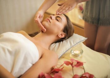 woman in wrapped in white towel lying on bed getting massage