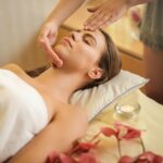woman in wrapped in white towel lying on bed getting massage
