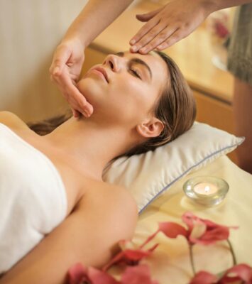 woman in wrapped in white towel lying on bed getting massage