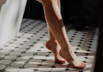person in white pants standing on white and black floor tiles